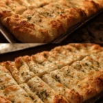 Homemade cheesy garlic breadsticks with melted cheese and herbs.